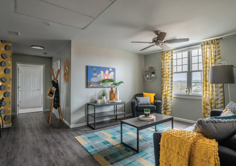 Vibrant living room with modern furniture, gray wood flooring and wallpaper with fruit graphics.